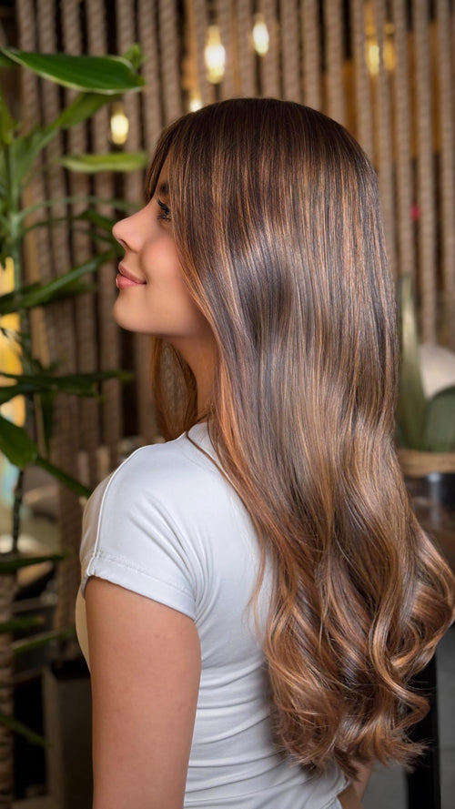 Woman with long, wavy hair in a softly lit indoor setting